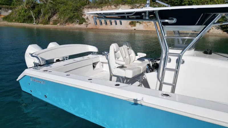 Reel Chaos Yacht Photos Pics 2022 Bahama 35 Open boat with blue hull, docked near a scenic shoreline.