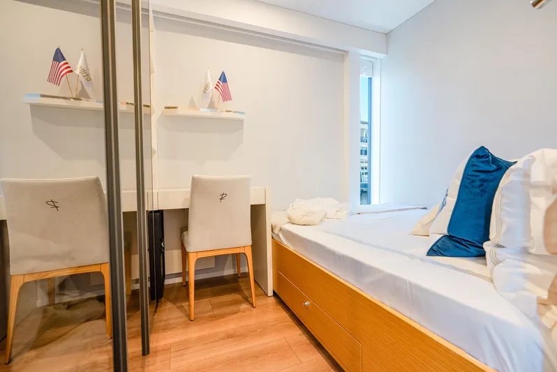  Yacht Photos Pics Modern hotel room with twin beds, blue pillows, and a small desk.