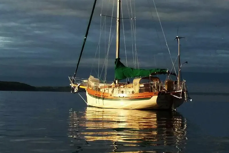 Jolie Brise Yacht Photos Pics 1985 Sam L. Morse Bristol Channel Cutter 28 sailboat on calm water at sunset.