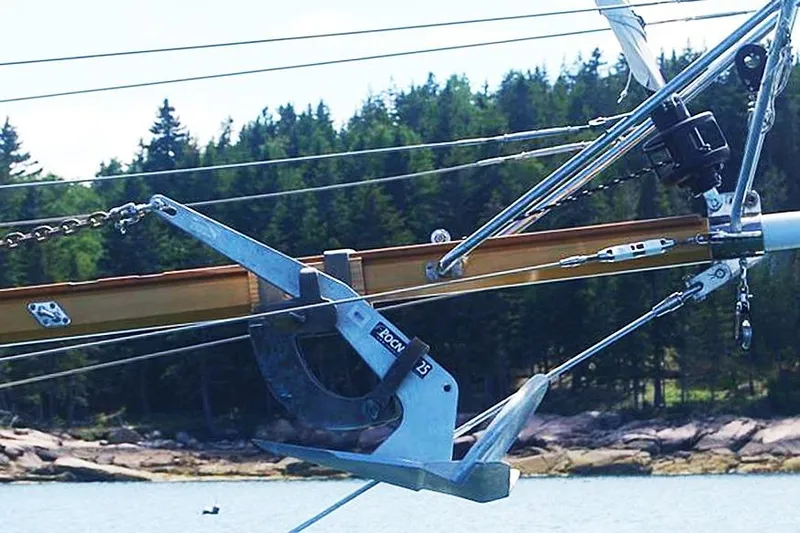 Jolie Brise Yacht Photos Pics Anchor detail on 1985 Sam L. Morse Bristol Channel Cutter 28 sailboat, with forested shoreline background.