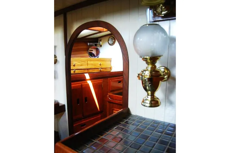 Jolie Brise Yacht Photos Pics Interior of 1985 Sam L. Morse Bristol Channel Cutter 28, featuring wood cabinetry and brass lamp.