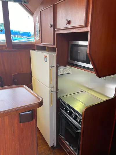 Kylieb Yacht Photos Pics 1986 Chris-Craft 422 Commander yacht kitchen with wood cabinets, fridge, stove, and microwave.