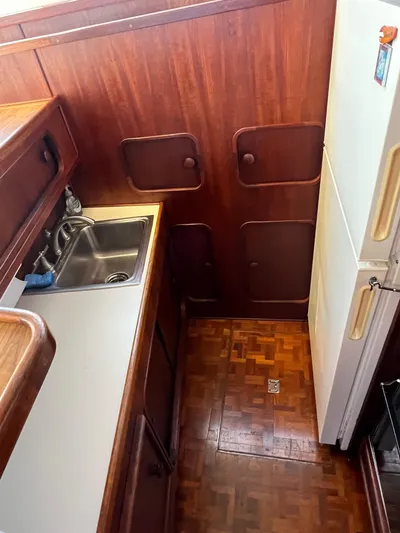 Kylieb Yacht Photos Pics 1986 Chris-Craft 422 Commander kitchen with wood paneling, sink, and refrigerator.