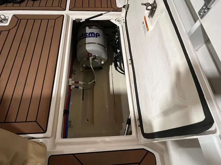 Regulus Yacht Photos Pics 2023 Ranger Tugs R-25 boat storage compartment with water heater and wooden flooring.