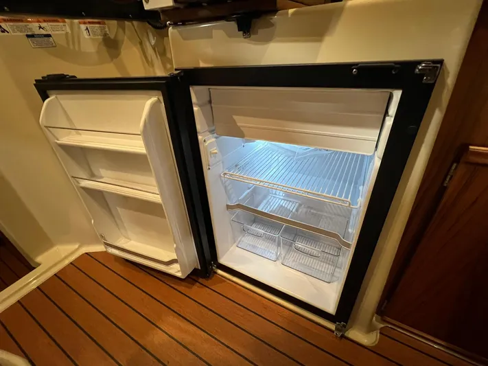 Regulus Yacht Photos Pics 2023 Ranger Tugs R-25 interior fridge with open door, showcasing shelves and storage space.