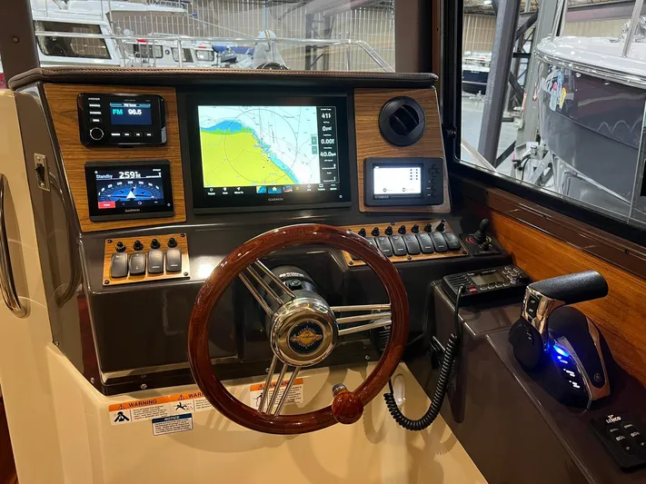 Regulus Yacht Photos Pics 2023 Ranger Tugs R-25 helm with navigation screens and wooden steering wheel.