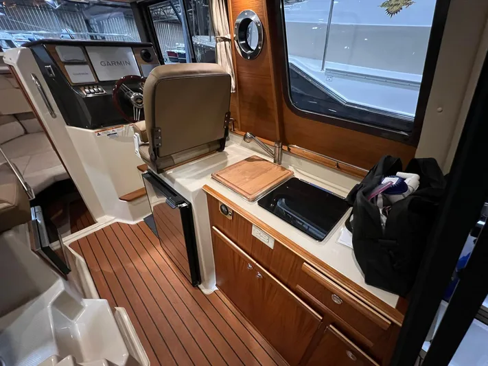 Regulus Yacht Photos Pics 2023 Ranger Tugs R-25 interior with helm, kitchenette, and wood accents.