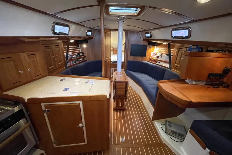 Rhyme Yacht Photos Pics Interior of a 2007 Tartan 3400 sailboat with wooden cabinetry and blue seating.