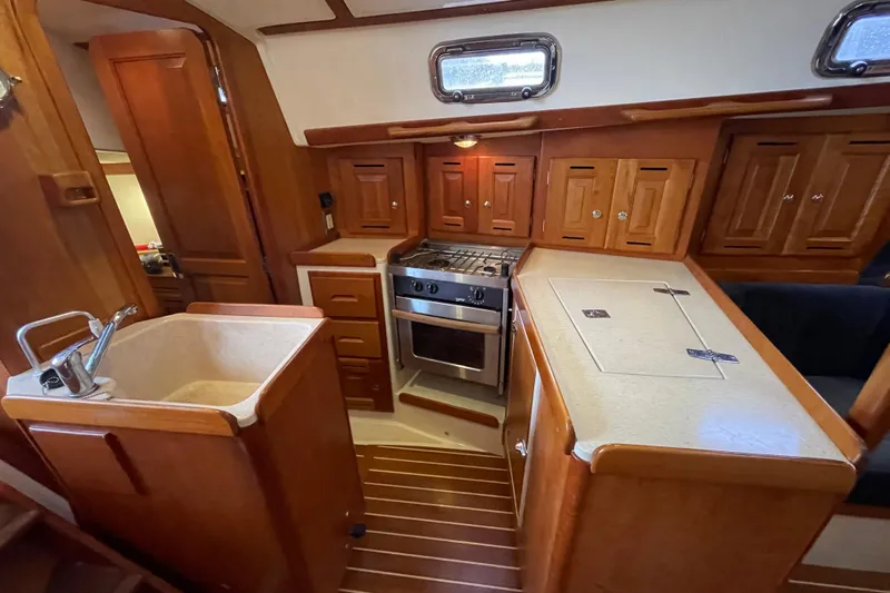 Rhyme Yacht Photos Pics 2007 Tartan 3400 yacht interior kitchen with wooden cabinetry and modern appliances.