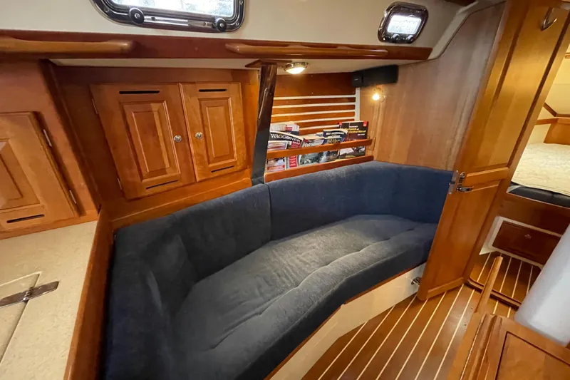 Rhyme Yacht Photos Pics Cozy interior of 2007 Tartan 3400 sailboat with wooden cabinets and blue cushioned seating.