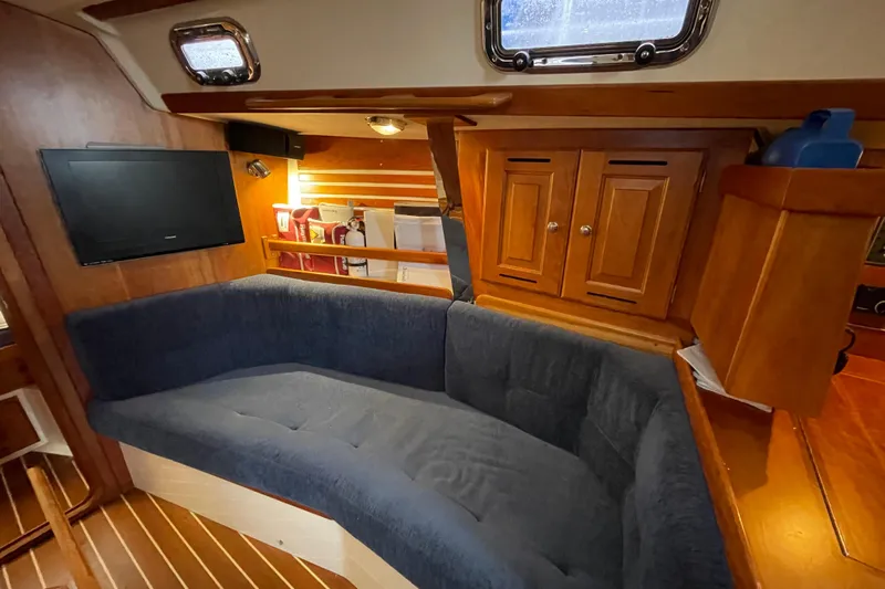 Rhyme Yacht Photos Pics Cozy interior of 2007 Tartan 3400 sailboat with blue seating and wooden cabinetry.