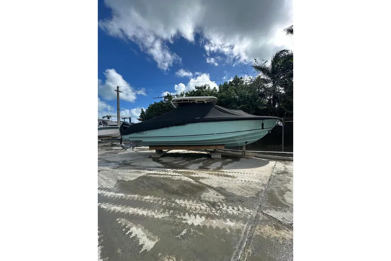  Yacht Photos Pics 2022 Boston Whaler 330 Outrage boat covered, parked outdoors under a cloudy sky.