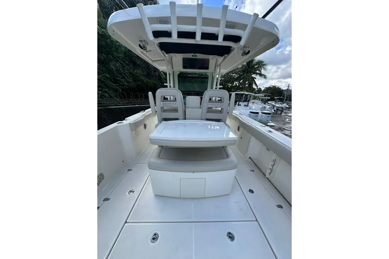  Yacht Photos Pics 2022 Boston Whaler 330 Outrage boat interior with seating and table, docked outdoors.