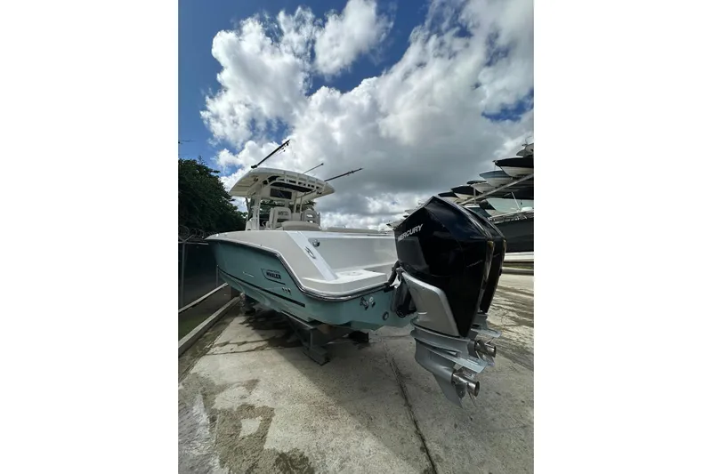  Yacht Photos Pics 2022 Boston Whaler 330 Outrage boat with Mercury outboard, docked under cloudy sky.