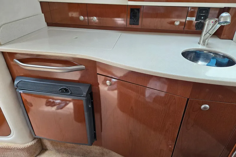 No Woke Zone Yacht Photos Pics 2008 Sea Ray 310 Sundancer interior kitchenette with sink, fridge, and wooden cabinetry.