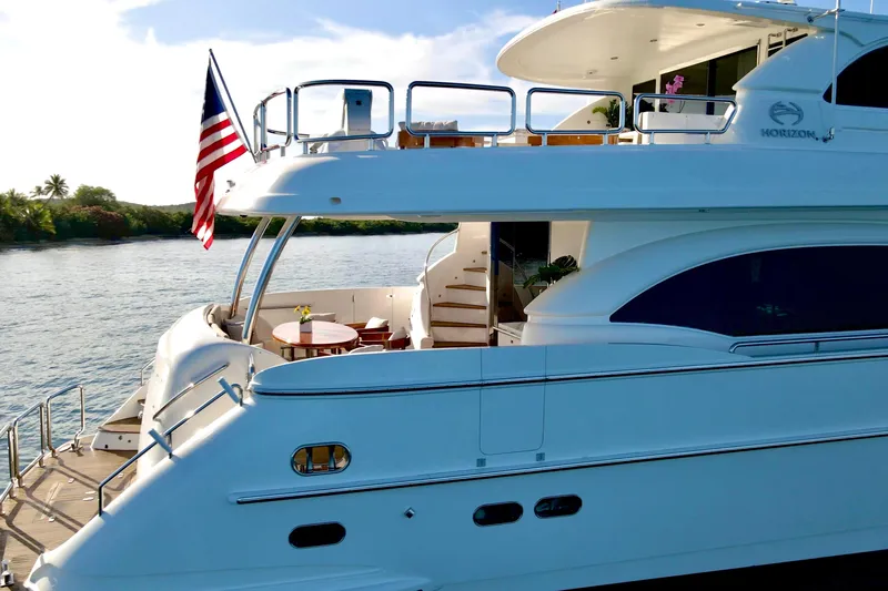 Tortuga Yacht Photos Pics Luxurious 2011 Horizon E88 yacht with American flag, docked by serene waters.