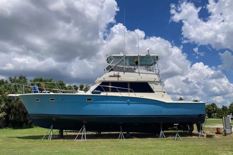 Golden Olive Yacht Photos Pics 1985 Hatteras Sportfish boat on land under cloudy sky.