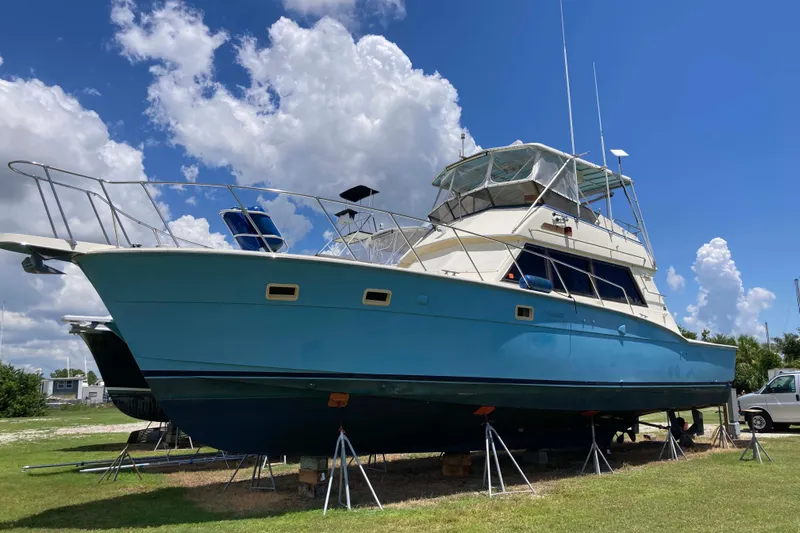 Golden Olive Yacht Photos Pics 1985 Hatteras Sportfish boat on stands under a bright blue sky.