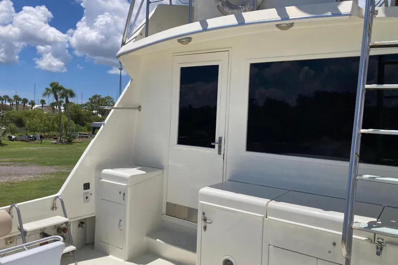 Golden Olive Yacht Photos Pics 1985 Hatteras Sportfish boat deck with storage, ladder, and scenic background.