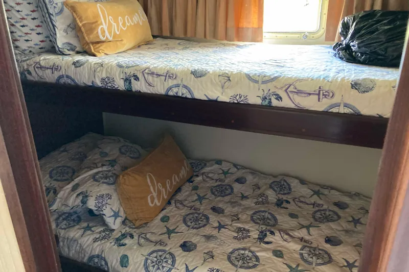Golden Olive Yacht Photos Pics Bunk beds with nautical-themed bedding in a 1985 Hatteras Sportfish cabin.