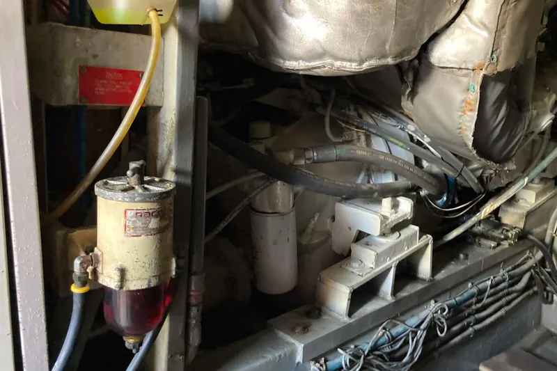 Golden Olive Yacht Photos Pics Engine compartment of a 1985 Hatteras Sportfish boat, showing mechanical components and hoses.