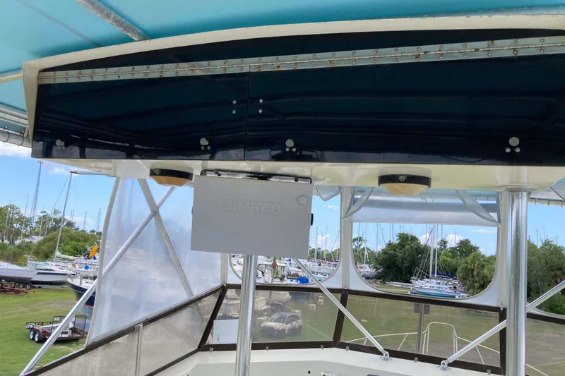 Golden Olive Yacht Photos Pics 1985 Hatteras Sportfish boat interior with Simrad equipment, marina view in background.