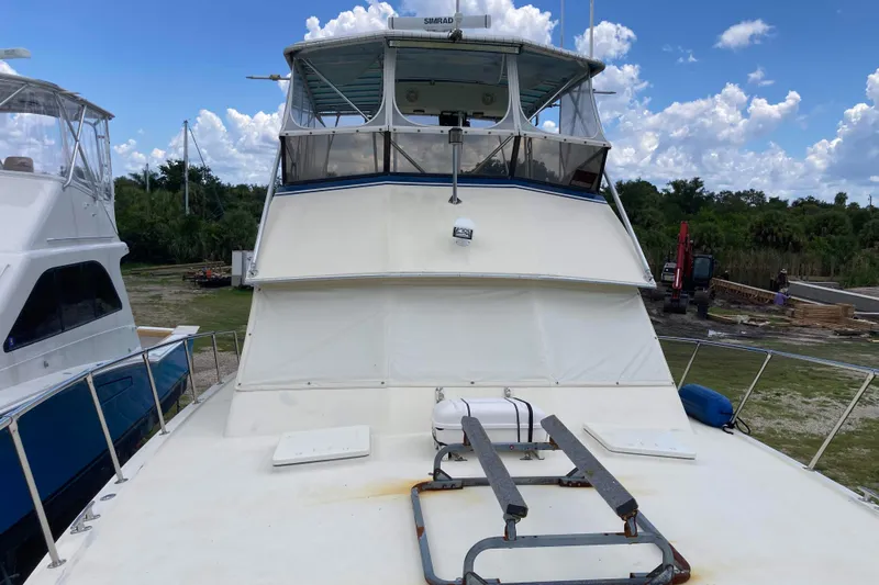 Golden Olive Yacht Photos Pics 1985 Hatteras Sportfish boat docked, featuring a spacious deck and enclosed flybridge.