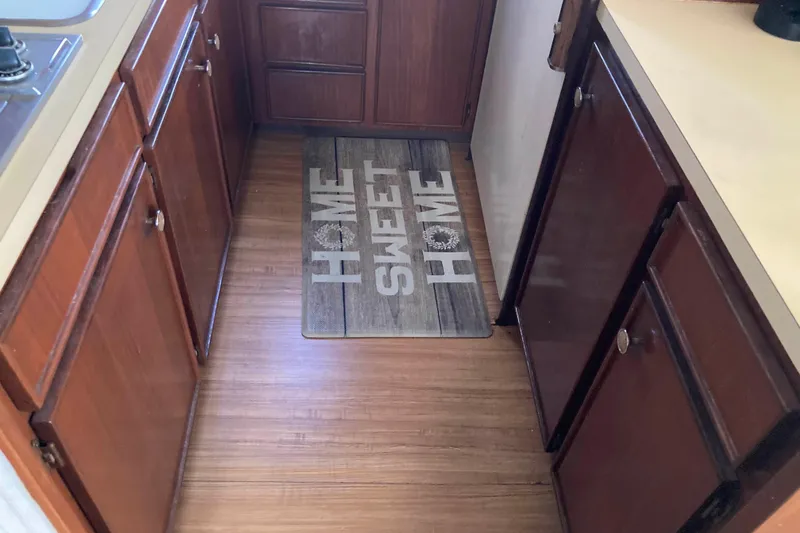 Golden Olive Yacht Photos Pics 1985 Hatteras Sportfish kitchen with wooden cabinets and "Home Sweet Home" mat.