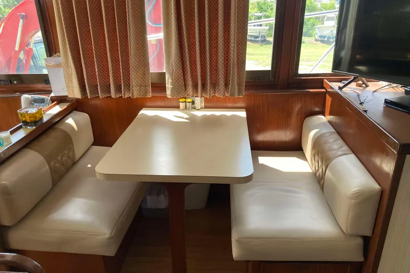 Golden Olive Yacht Photos Pics 1985 Hatteras Sportfish interior with dining booth, wood paneling, and large windows.