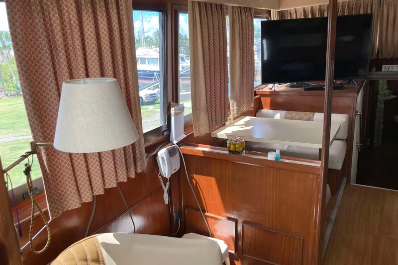 Golden Olive Yacht Photos Pics Interior of a 1985 Hatteras Sportfish yacht with wood paneling and a dining area.