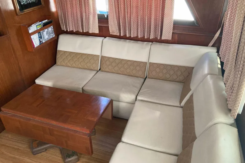 Golden Olive Yacht Photos Pics Interior of 1985 Hatteras Sportfish with beige seating and wooden table.
