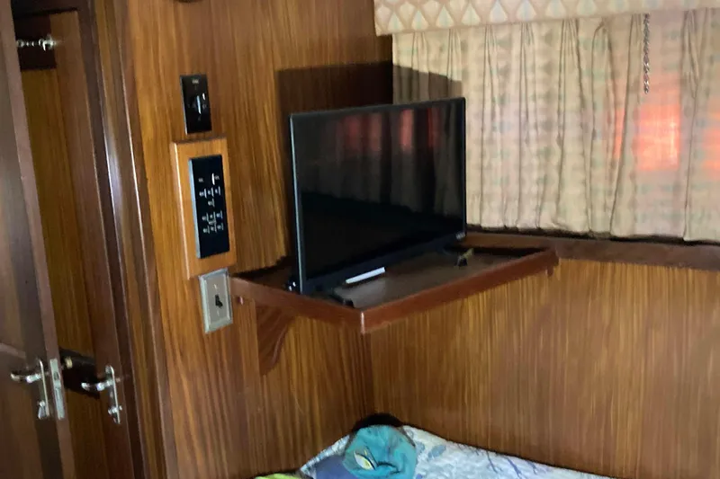 Golden Olive Yacht Photos Pics 1985 Hatteras Sportfish cabin interior with TV, wood paneling, and curtains.