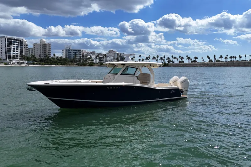  Yacht Photos Pics 2023 Scout 330 LXF boat on water with cityscape and palm trees in background.