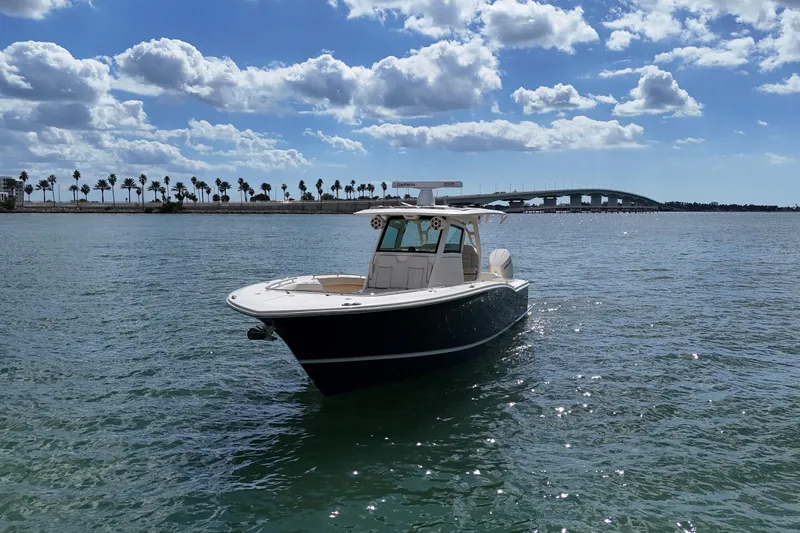  Yacht Photos Pics 2023 Scout 330 LXF boat on water with bridge and palm trees in background.