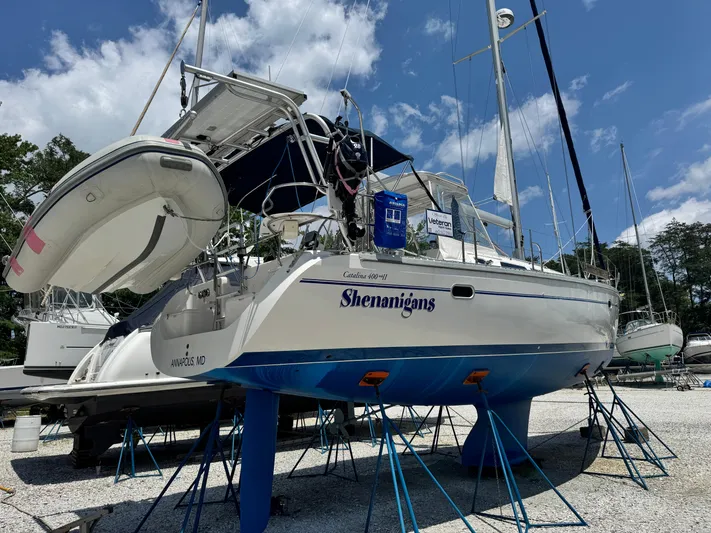 Shenanigans Yacht Photos Pics Catalina 400 MkII sailboat from 2001 on stands, with a dinghy attached, under a blue sky.