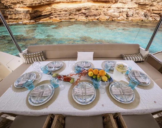 My Biscane Yacht Photos Pics Luxury dining setup on 2007 Astondoa A 76 GLX yacht, overlooking clear turquoise waters.