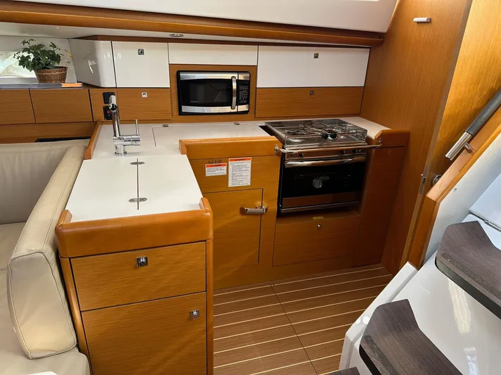 Life Line Yacht Photos Pics 2017 Jeanneau Sun Odyssey 44 DS yacht kitchen with stove, microwave, and wooden cabinetry.