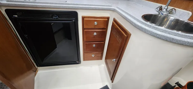Re-fit 2021-2024 With 2017 Cummins 540s Yacht Photos Pics 1995 Cabo 35 Express boat kitchen with sink, fridge, and wooden cabinets.