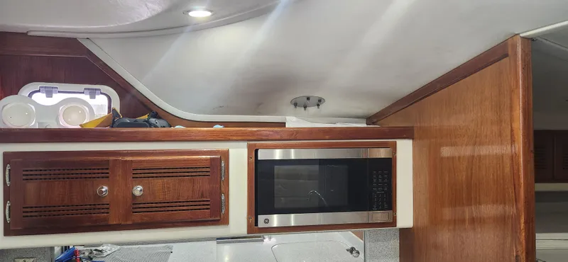 Re-fit 2021-2024 With 2017 Cummins 540s Yacht Photos Pics Interior of a 1995 Cabo 35 Express boat with wooden cabinets and a microwave.