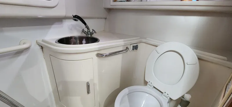 Re-fit 2021-2024 With 2017 Cummins 540s Yacht Photos Pics Compact bathroom in a 1995 Cabo 35 Express boat with sink and toilet.