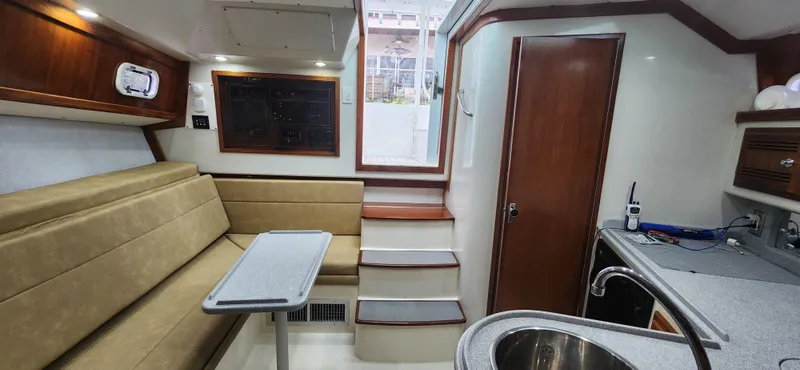 Re-fit 2021-2024 With 2017 Cummins 540s Yacht Photos Pics Interior of 1995 Cabo 35 Express boat with seating, table, and kitchenette.