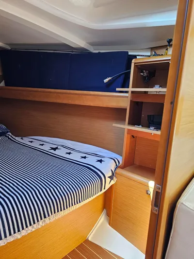Tharos Yacht Photos Pics 2016 Jeanneau 379 cabin interior with striped bedding and wooden shelves.
