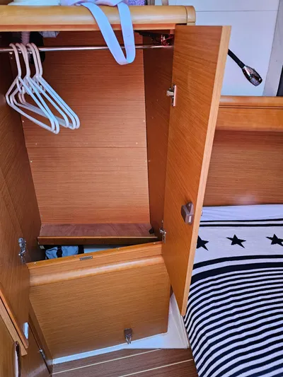 Tharos Yacht Photos Pics Interior of 2016 Jeanneau 379 sailboat showing wooden closet with hangers and striped bedding.