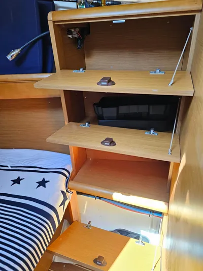 Tharos Yacht Photos Pics Interior storage shelves on a 2016 Jeanneau 379 sailboat, featuring wooden compartments and nautical bedding.