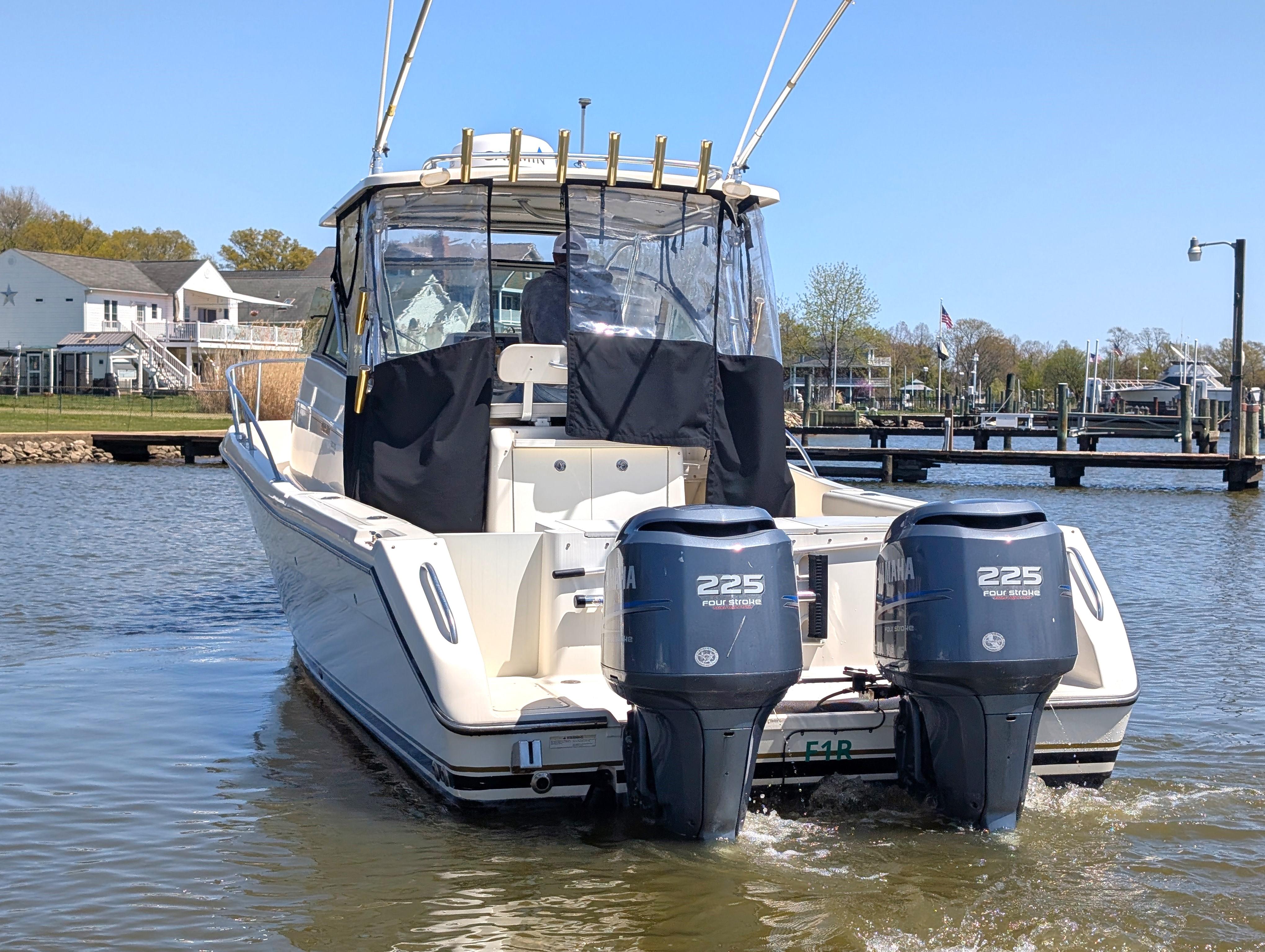 2001 Pursuit 3070 Offshore Center Console boat with twin 225 horsepower engines on a calm waterway.