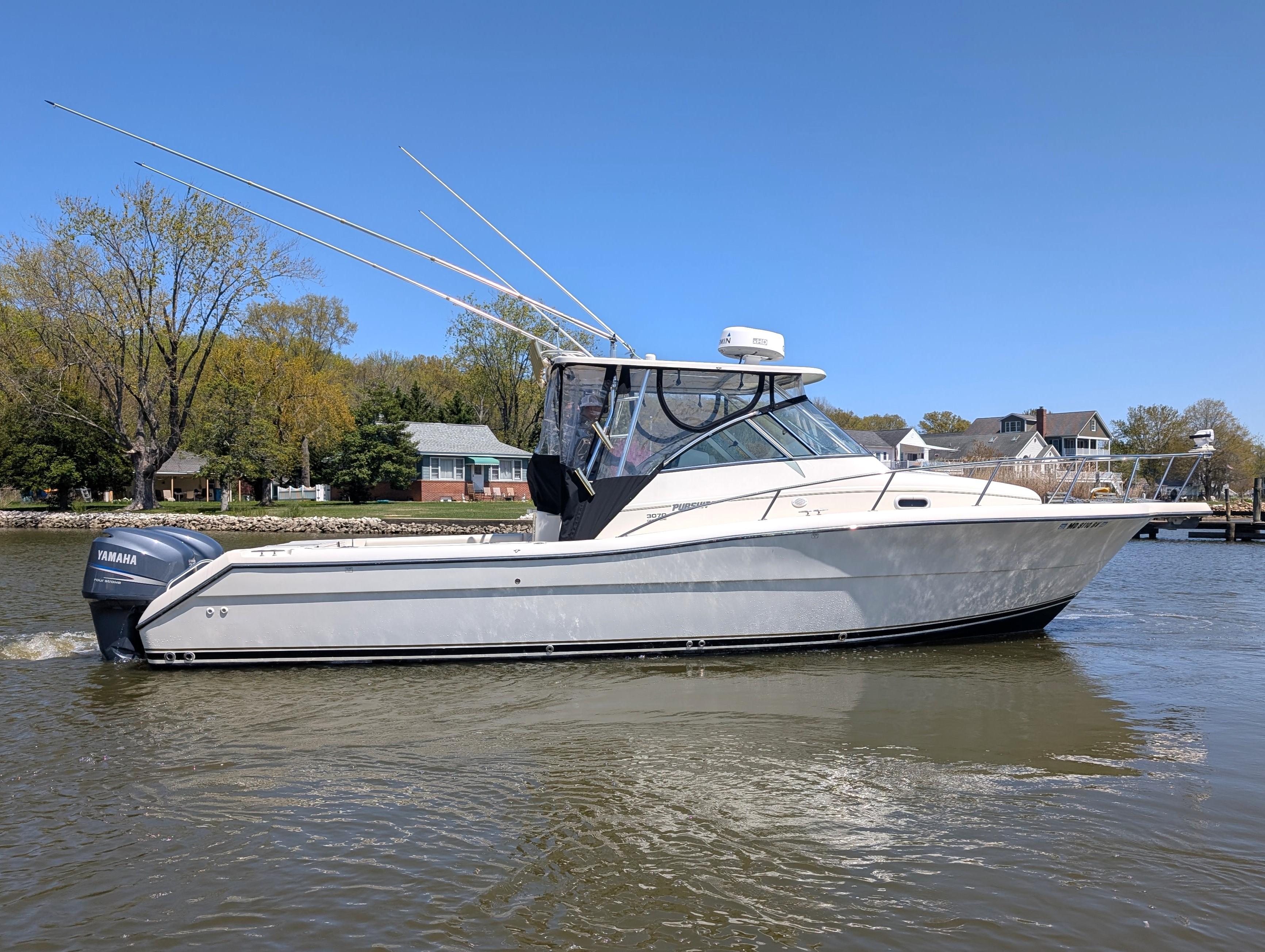 2001 Pursuit 3070 Offshore Center Console boat on calm water, clear sky background.