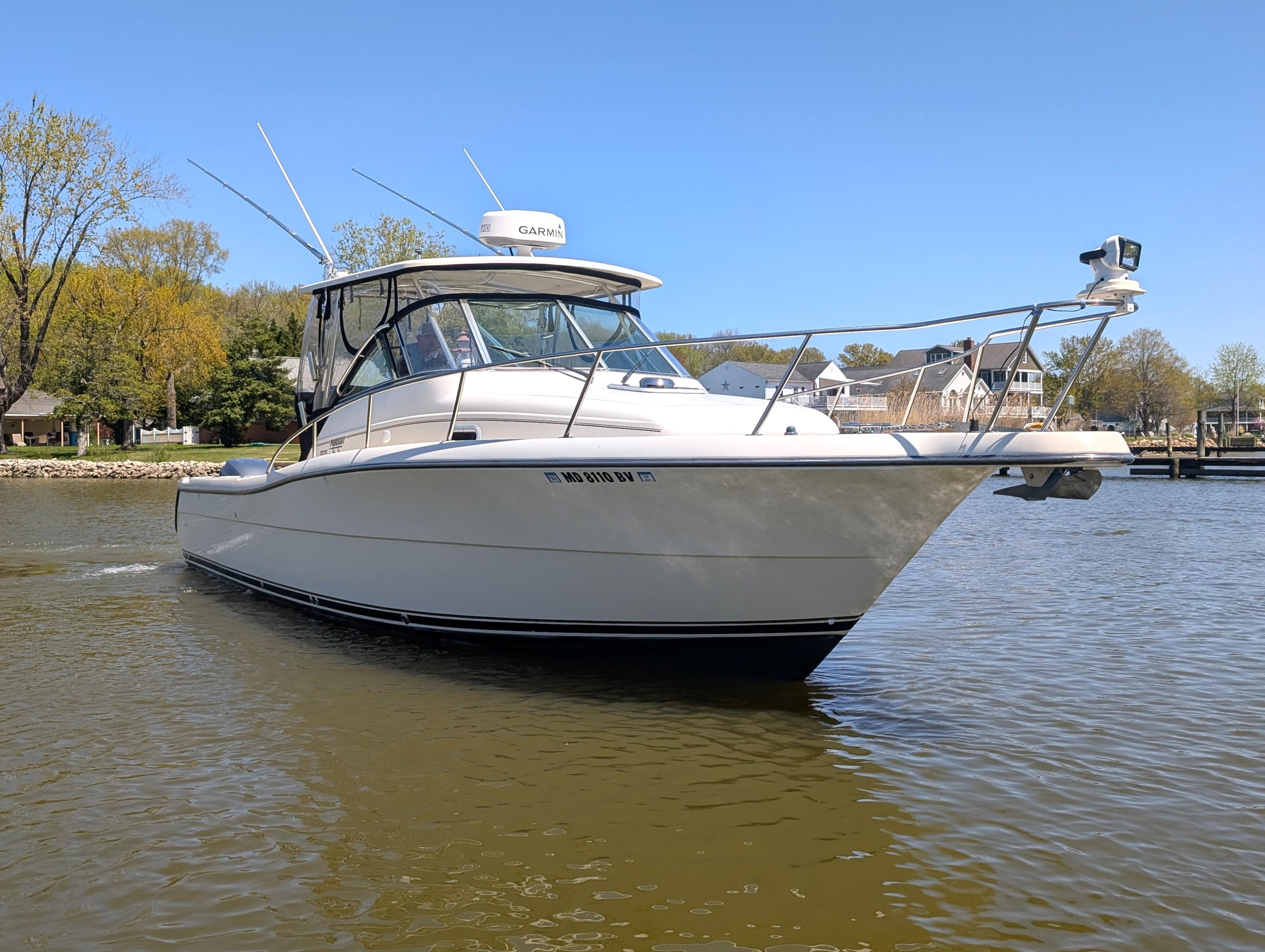 2001 Pursuit 3070 Offshore Center Console boat on calm water, clear sky background.