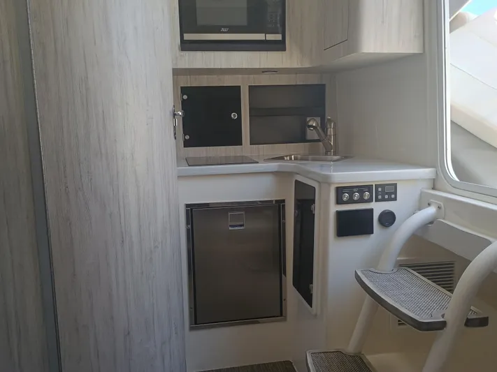 41-083 Yacht Photos Pics 2023 Regulator 41 boat interior with compact kitchenette, featuring sink, microwave, and storage cabinets.