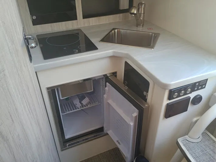 41-083 Yacht Photos Pics Compact kitchen area in 2023 Regulator 41 boat with sink, stove, and open fridge.