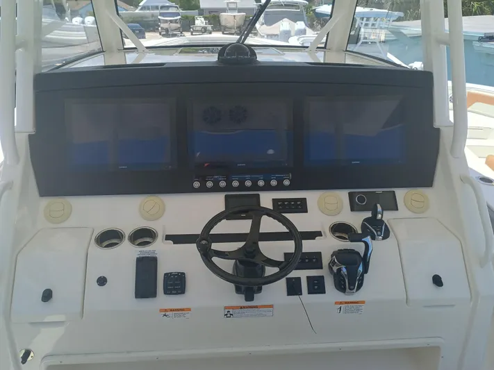 41-083 Yacht Photos Pics Control panel of a 2023 Regulator 41 boat with multiple screens and steering wheel.